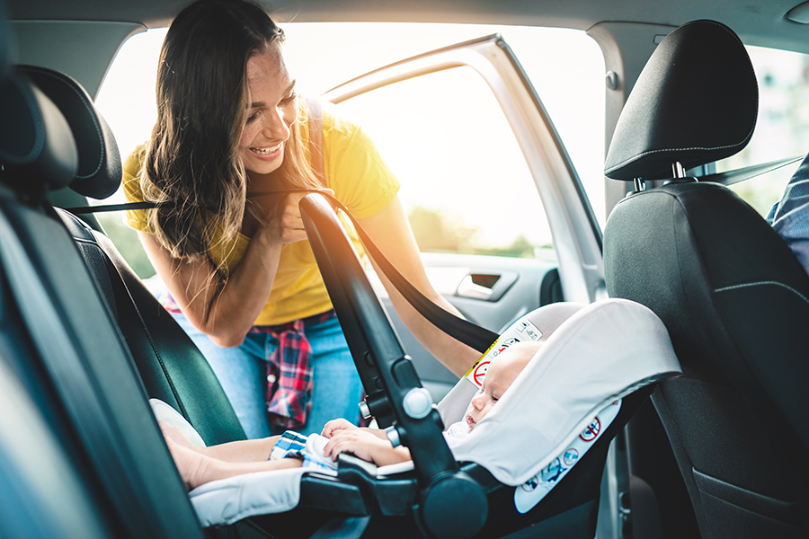 Mother securing rear-facing infant car seat